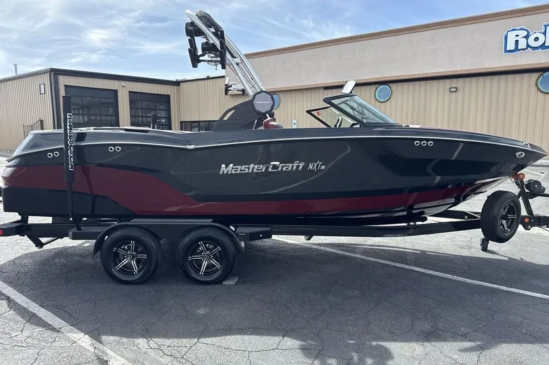 Slide: The Image of 2023 MasterCraft NXT22 boat on trailer, parked outside a building. - 6