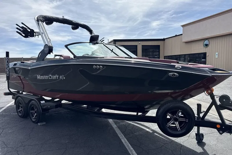 Slide: The Image of 2023 MasterCraft NXT22 boat on trailer, parked outdoors under a cloudy sky. - 7