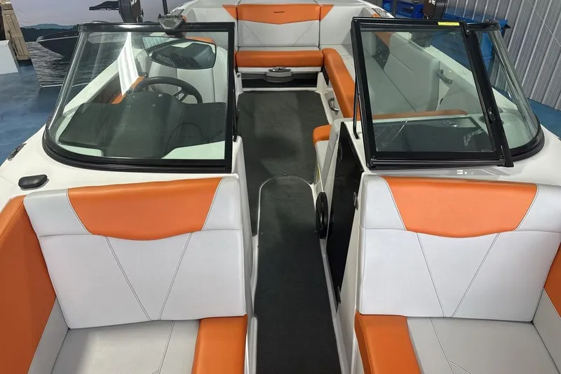 Slide: The Image of 2021 MasterCraft NXT24 boat interior with orange and white seating, open windshield, and steering wheel. - 12