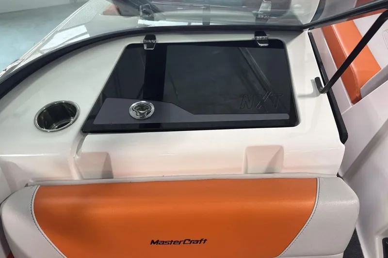 Slide: The Image of 2021 MasterCraft NXT24 boat interior with orange seating and storage compartment. - 18