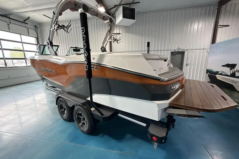 Slide: The Image of 2021 MasterCraft NXT24 boat in showroom, featuring sleek design and dual-axle trailer. - 3