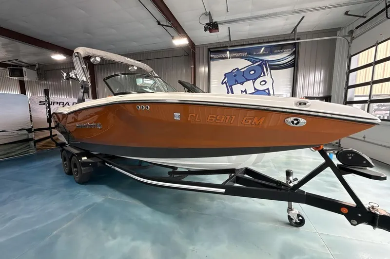 Slide: The Image of 2021 MasterCraft NXT24 boat in showroom, orange hull, on trailer. - 7