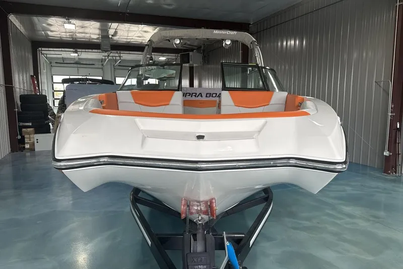Slide: The Image of 2021 MasterCraft NXT24 boat in showroom, white with orange interior accents. - 8