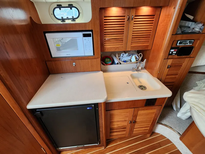 Slide: The Image of Compact galley kitchen in 2000 Pursuit 3400 Express boat with microwave, sink, and mini-fridge. - 12