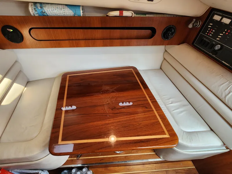 Slide: The Image of Interior of a 2000 Pursuit 3400 Express boat with a wooden table and white seating. - 15