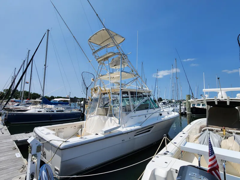 Slide: The Image of 2000 Pursuit 3400 Express boat docked at a marina on a sunny day. - 2
