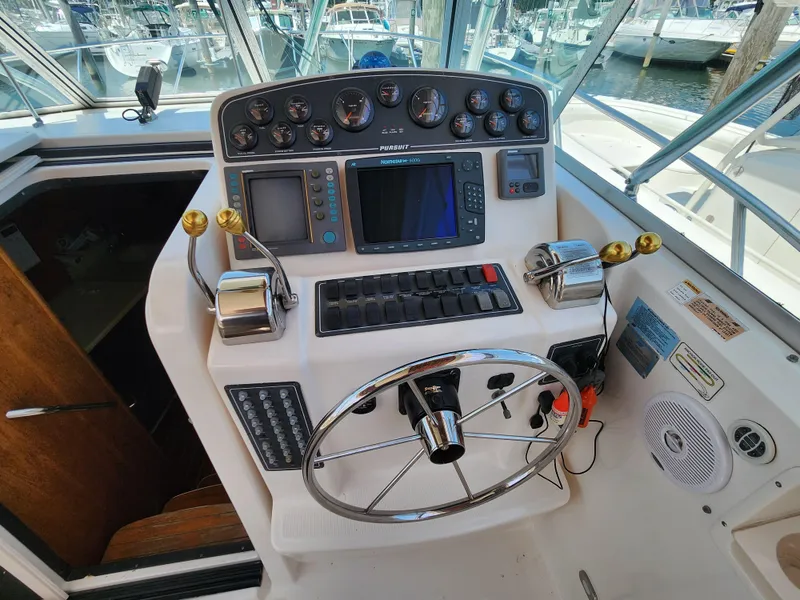 Slide: The Image of Control panel of a 2000 Pursuit 3400 Express boat with steering wheel and navigation instruments. - 8