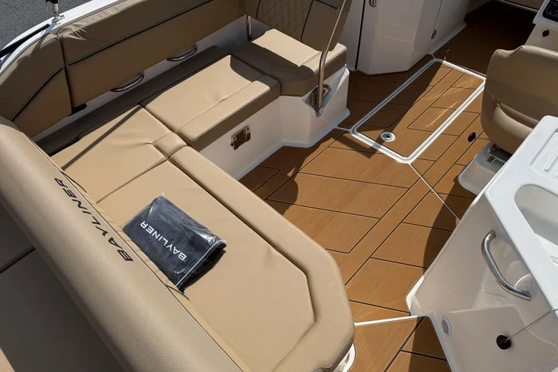 Slide: The Image of 2026 Bayliner D22I boat interior with tan seating and wood-patterned flooring. - 3