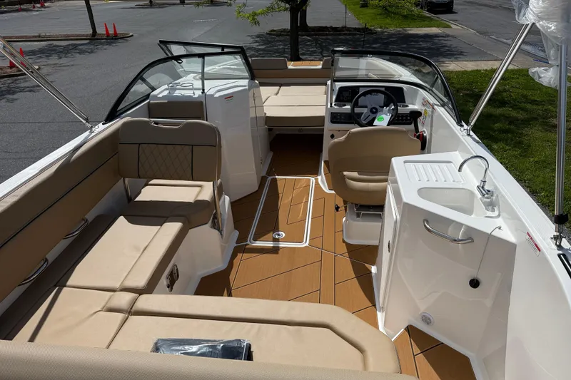 Slide: The Image of 2026 Bayliner D22I boat interior with beige seating, steering console, and sink. - 4