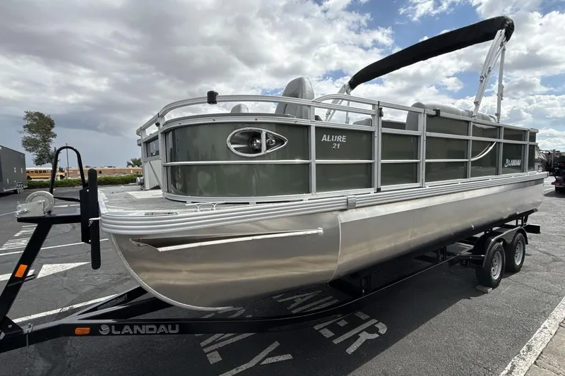 The Image of 2026 Landau Alure pontoon boat on trailer under cloudy sky. - 1