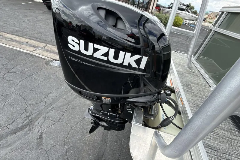 Slide: The Image of Suzuki four-stroke outboard motor on a 2026 Landau Alure boat, parked on pavement. - 19