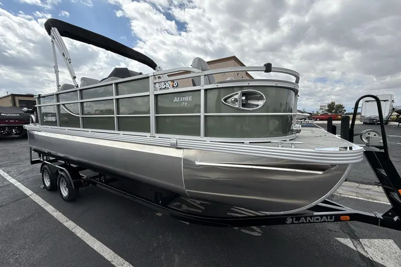 Slide: The Image of 2026 Landau Alure pontoon boat on trailer, parked outdoors under cloudy sky. - 7