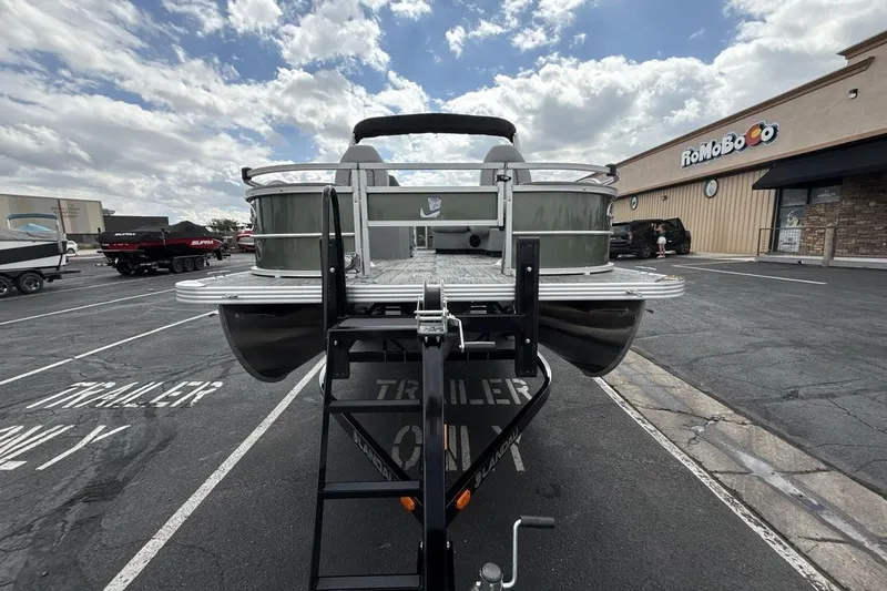 Slide: The Image of 2026 Landau Alure pontoon boat on trailer in parking lot, cloudy sky background. - 8