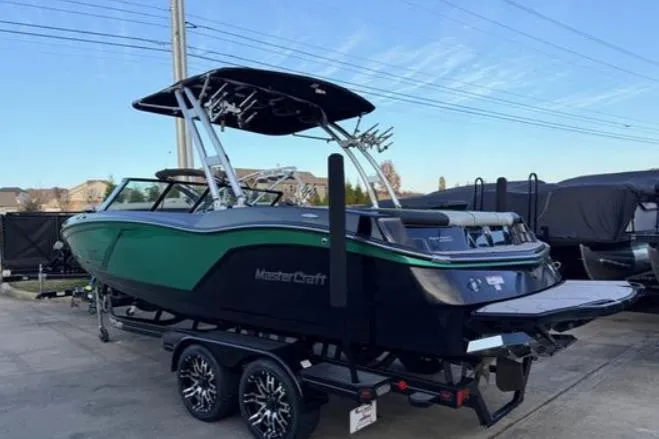 Slide: The Image of 2016 MasterCraft NXT22 boat on trailer, green and black design, parked outdoors. - 2