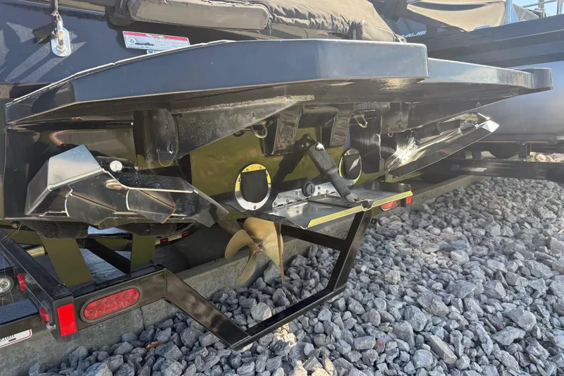 Slide: The Image of 2016 MasterCraft NXT22 boat stern with propeller and trailer on gravel surface. - 28