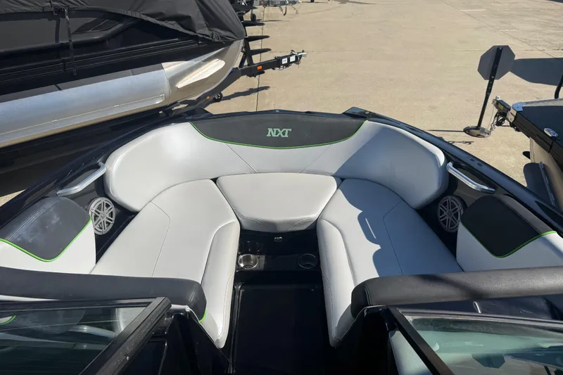 Slide: The Image of 2016 MasterCraft NXT22 boat interior with white and green seating, docked outdoors. - 3