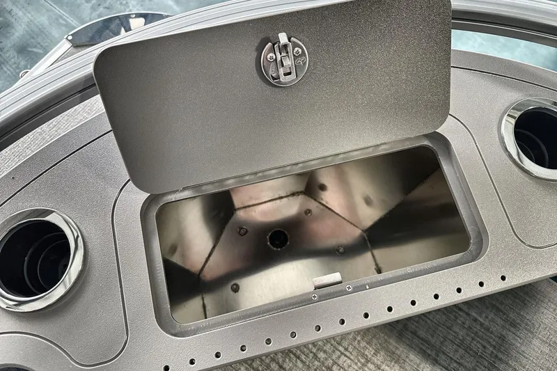 Slide: The Image of Open storage compartment on 2026 Landau Island Breeze 23F boat dashboard with cup holders. - 20