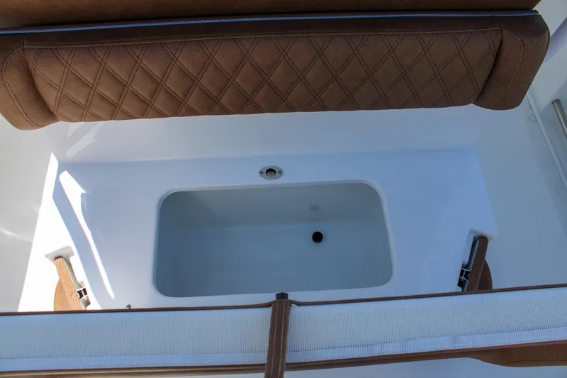 Slide: The Image of 2026 Sea Hunt Ultra 255 SE boat interior with brown cushioned seating and storage compartment. - 14