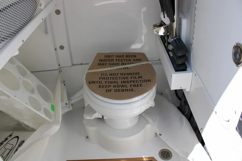 Slide: The Image of 2026 Sea Hunt Ultra 255 SE boat toilet with protective film and inspection notice. - 37