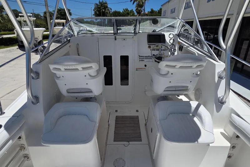 Slide: The Image of 2009 Sea Fox 256 Walk Around boat interior with dual white captain chairs and control panel. - 6