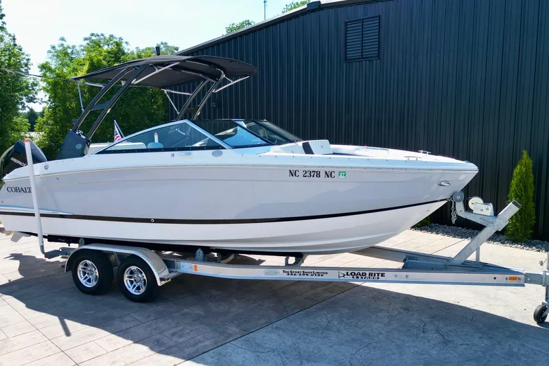 The Image of 2023 Cobalt R4 Outboard boat on trailer, parked outdoors near a black building. - 0