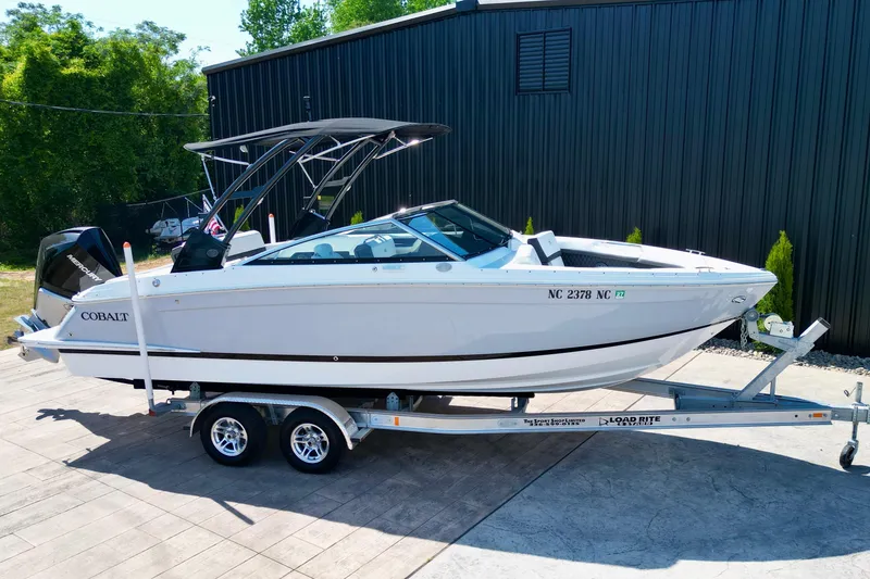 Slide: The Image of 2023 Cobalt R4 Outboard boat on trailer, parked outdoors near a black building. - 15