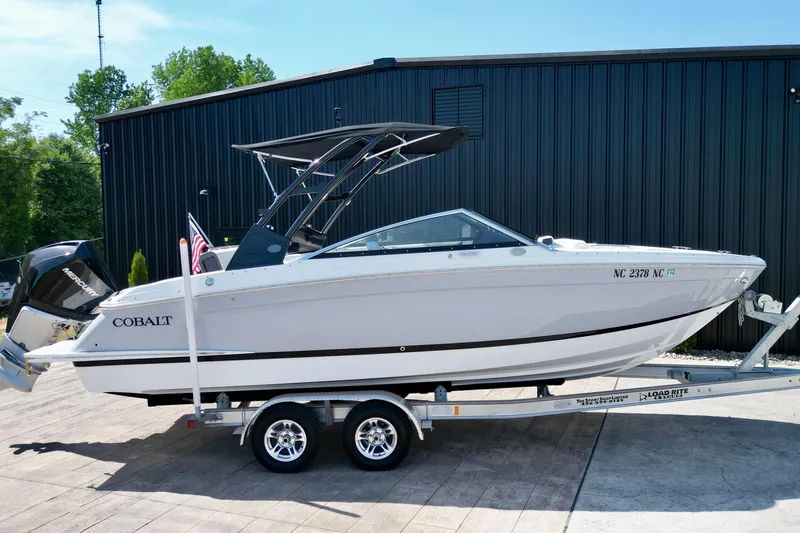 Slide: The Image of 2023 Cobalt R4 Outboard boat on trailer, parked outdoors near a black building. - 16