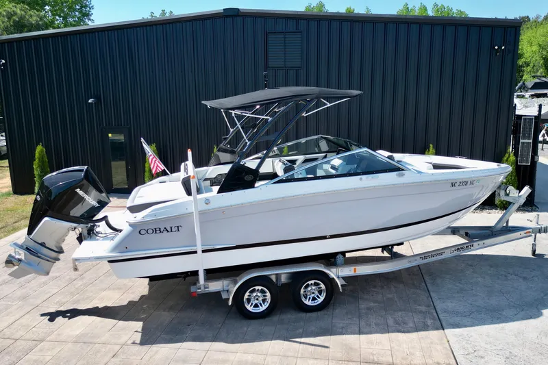 Slide: The Image of 2023 Cobalt R4 Outboard boat on trailer, parked outside a black building. - 17