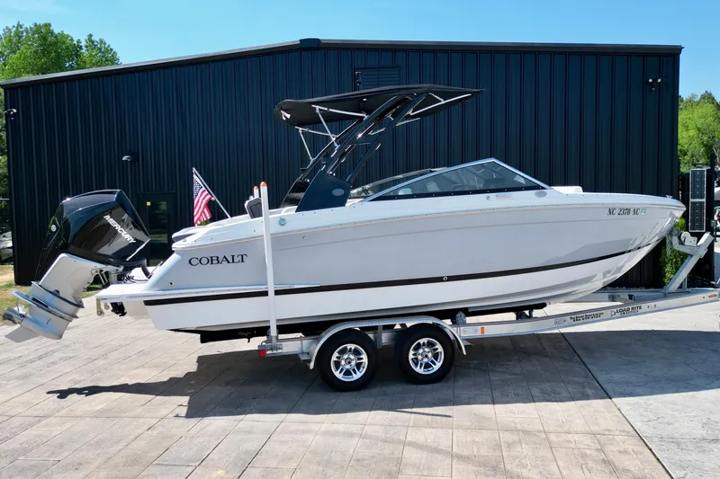 Slide: The Image of 2023 Cobalt R4 Outboard boat on trailer, parked outdoors near a black building. - 18