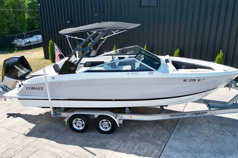 Slide: The Image of 2023 Cobalt R4 Outboard boat on trailer, sleek design, parked outdoors. - 2