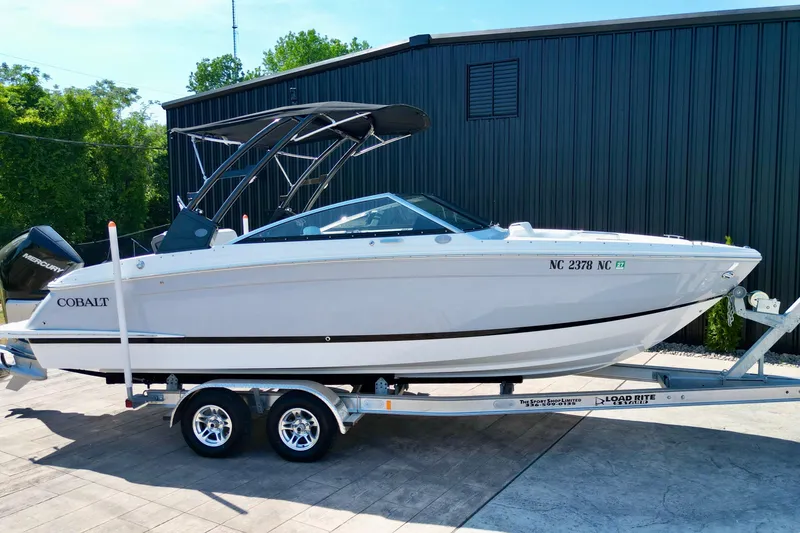 Slide: The Image of 2023 Cobalt R4 Outboard boat on trailer, parked outdoors near a building. - 7