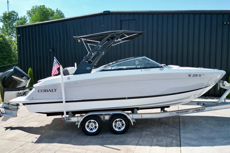 Slide: The Image of 2023 Cobalt R4 Outboard boat on trailer, displayed outdoors with American flag. - 8