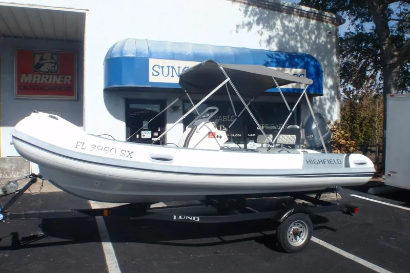 The Image of 2021 Highfield Sport 460 inflatable boat on trailer, parked outside a marine store. - 0