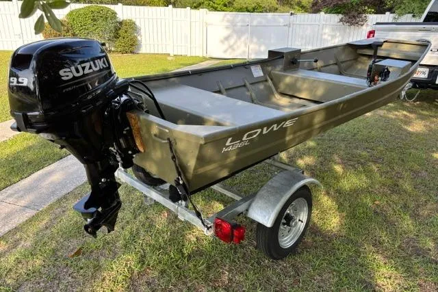 The Image of 2026 Lowe L1436 Jon boat with Suzuki 9.9 motor on trailer in yard. - 1