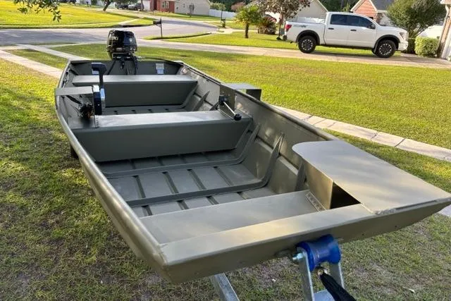 Slide: The Image of 2026 Lowe L1436 Jon boat on trailer, parked on grass in suburban neighborhood. - 3