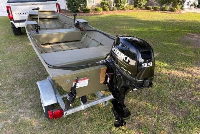 Slide: The Image of 2026 Lowe L1436 Jon boat with Suzuki 9.9 motor on trailer, parked on grass. - 4