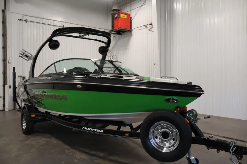 Slide: The Image of 2011 Moomba Mobius LSV boat in a garage, featuring a sleek green and black design. - 2