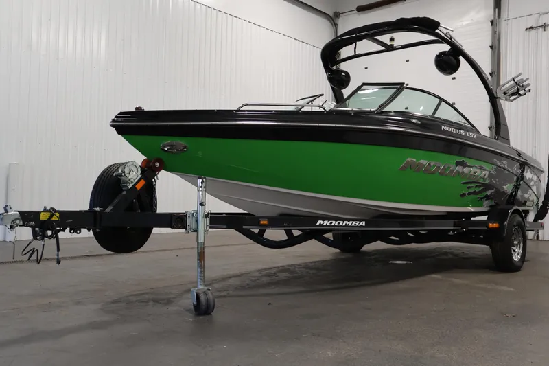Slide: The Image of 2011 Moomba Mobius LSV boat with green and black design on a trailer in a garage. - 47