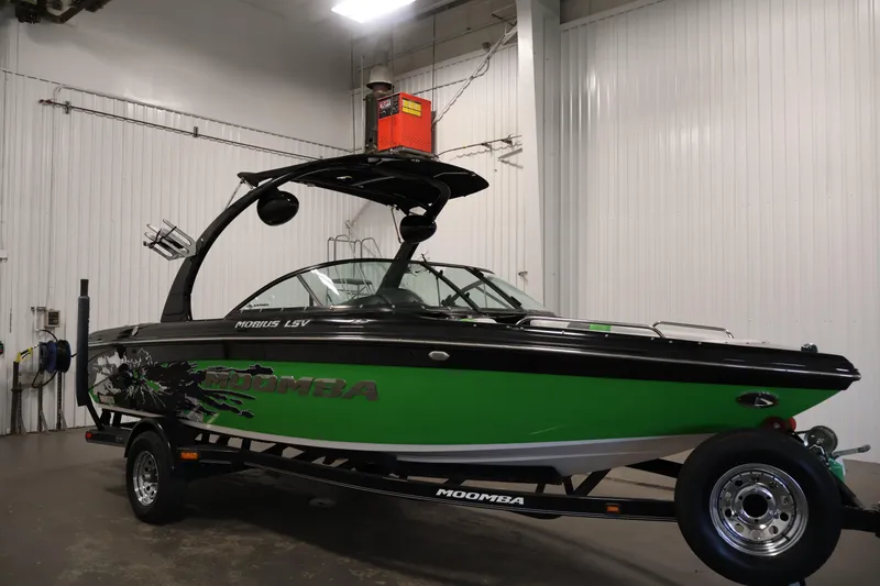 Slide: The Image of 2011 Moomba Mobius LSV boat in a garage, featuring a sleek green and black design. - 49