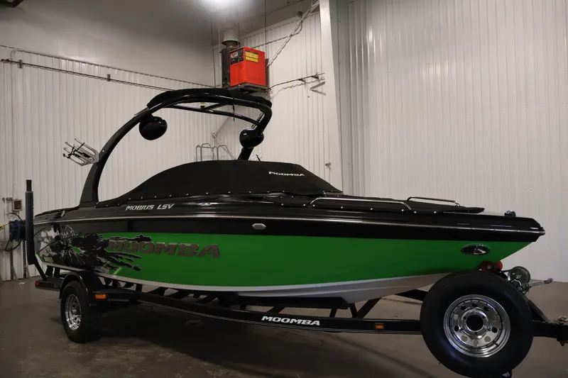 Slide: The Image of 2011 Moomba Mobius LSV boat in a garage, featuring a vibrant green and black design. - 50