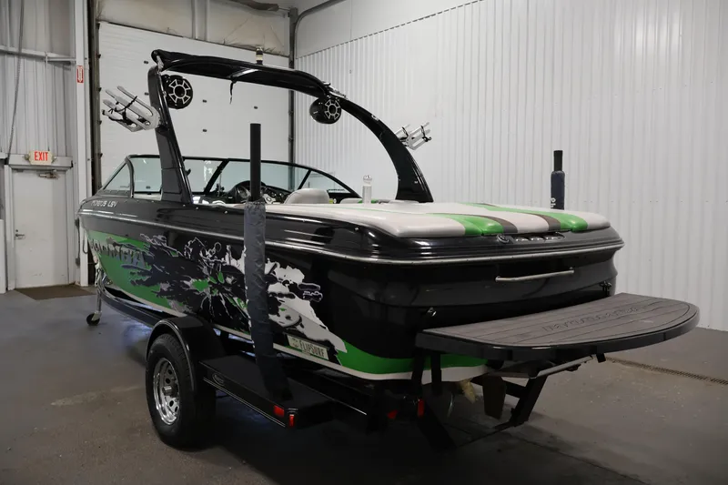 Slide: The Image of 2011 Moomba Mobius LSV boat with vibrant green and black design in a garage setting. - 6