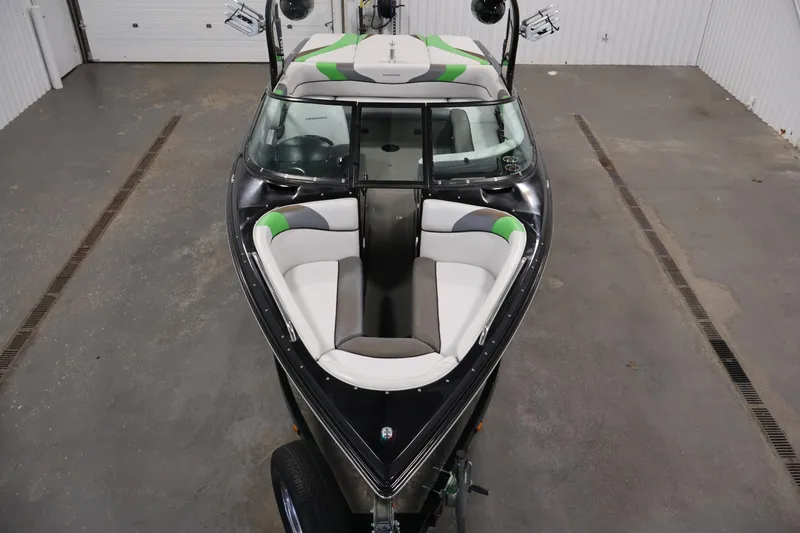 Slide: The Image of 2011 Moomba Mobius LSV boat with sleek design and green accents in a garage setting. - 8