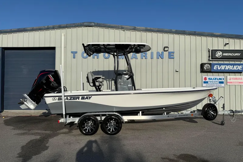 The Image of 2026 Blazer Bay PURE BAY 2200 boat on trailer outside marine dealership. - 1