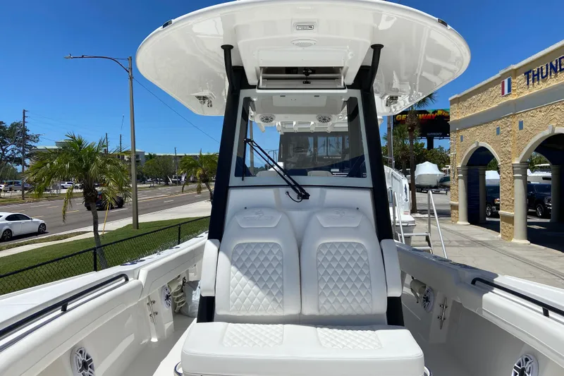 Slide: The Image of 2026 Regulator 28 boat with white seating and T-top, parked near a street. - 15