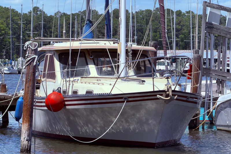 Slide: The Image of 1985 Lancer Yachts 40 Motorsailer docked at marina, surrounded by sailboats and trees. - 1