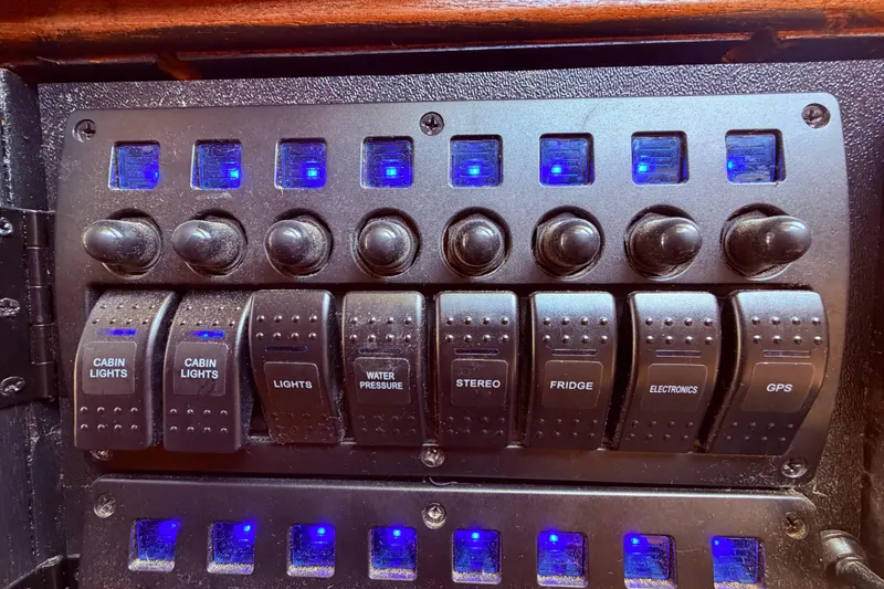 Slide: The Image of Control panel of a 1985 Lancer Yachts 40 Motorsailer with labeled switches and blue lights. - 49