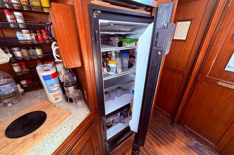 Slide: The Image of Open refrigerator in 1985 Lancer Yachts 40 Motorsailer galley, surrounded by spices and kitchen essentials. - 64