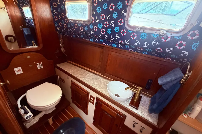 Slide: The Image of 1985 Lancer Yachts 40 Motorsailer bathroom with nautical decor, wooden cabinetry, and modern fixtures. - 66