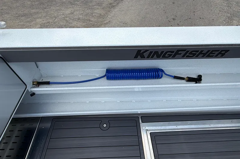 Slide: The Image of KingFisher 2825 Coastal Express 2026 boat deck with coiled blue hose and storage compartment. - 27