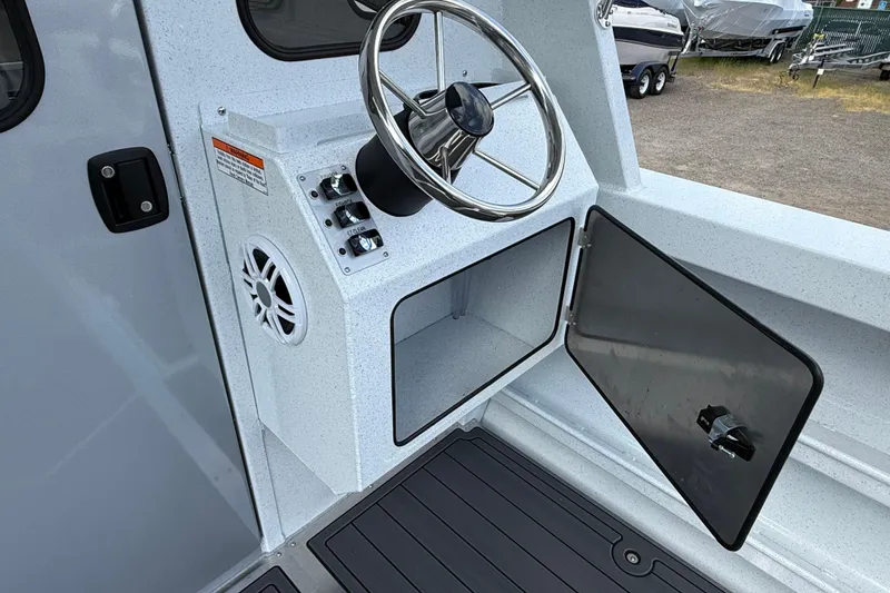 Slide: The Image of Steering console of 2026 KingFisher 2825 Coastal Express boat with open storage compartment. - 31